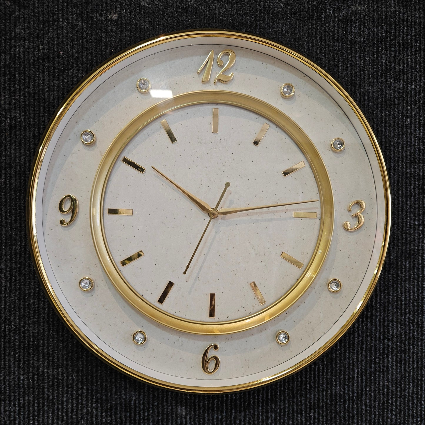 Decorative wall clock with gold rim and white face on a black background