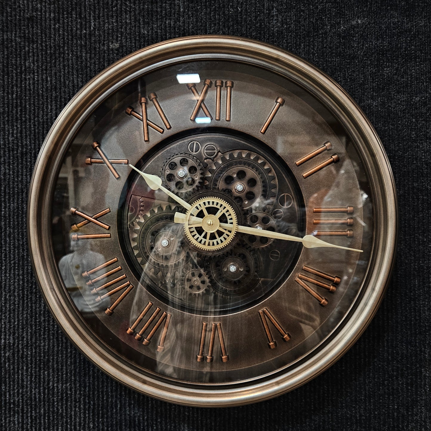 Decorative clock with Roman numerals and visible gears on a black background