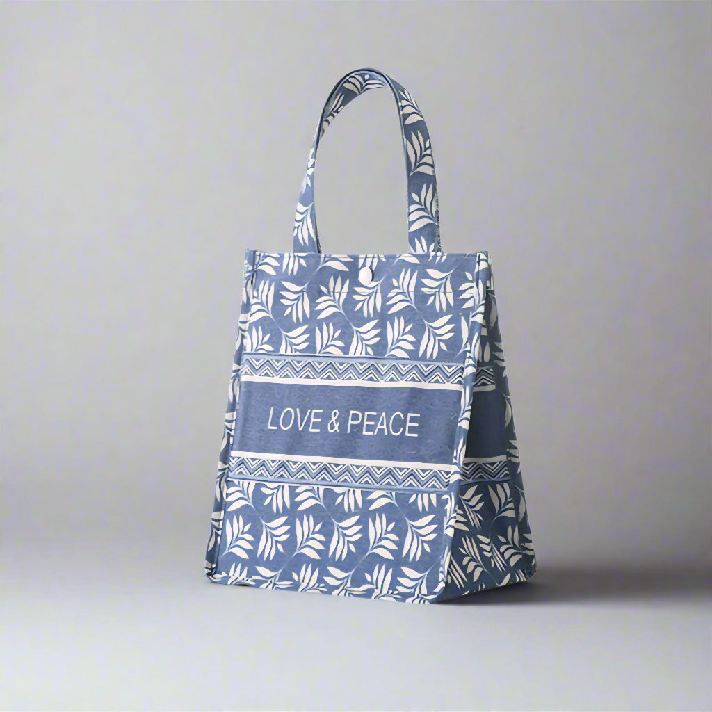 Blue tote bag with white leaf pattern and 'Love & Peace' text on a white background