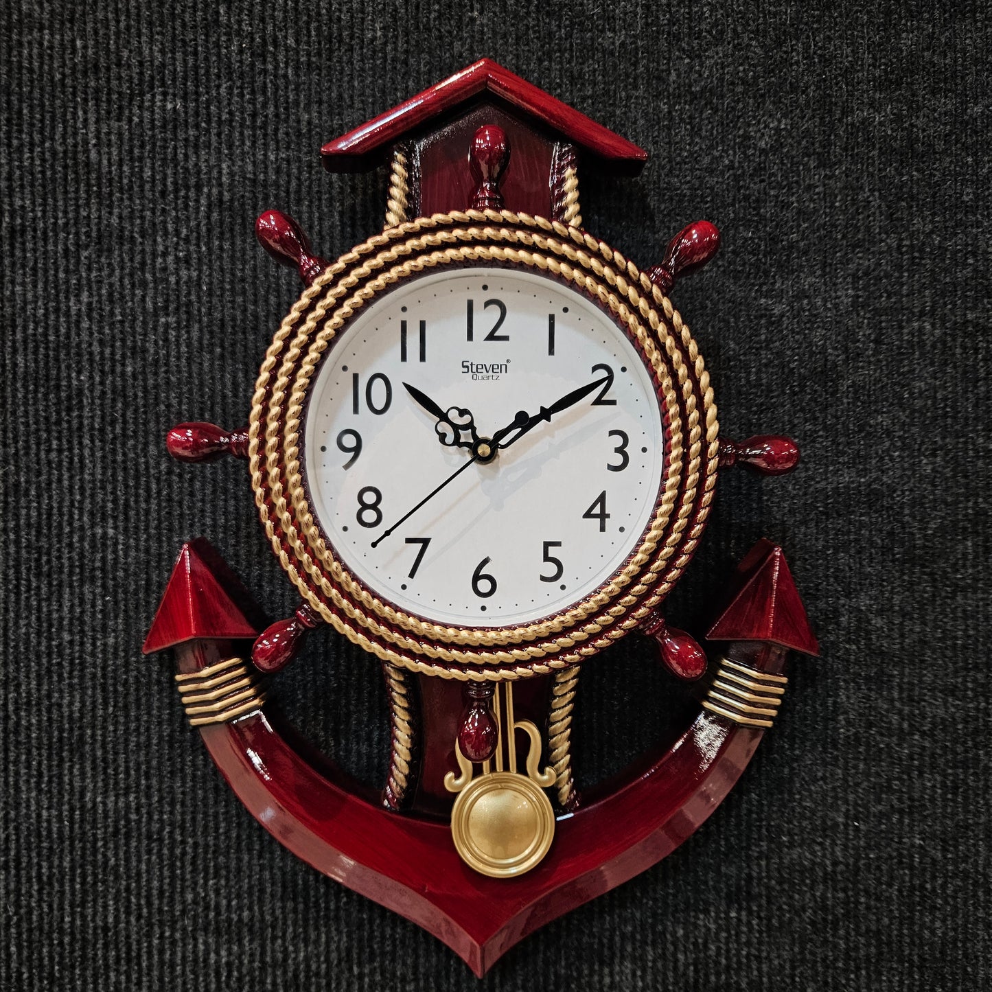 Decorative wall clock with red and gold accents on a dark textured background