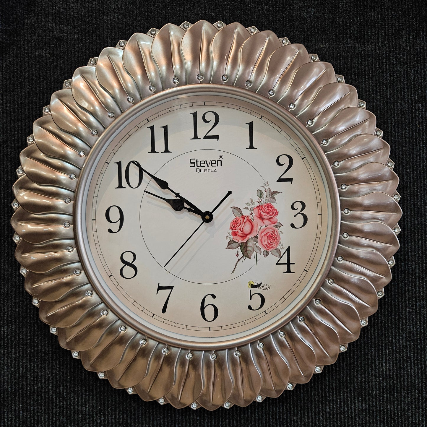 Decorative wall clock with floral design and 'Steven' brand on a black background