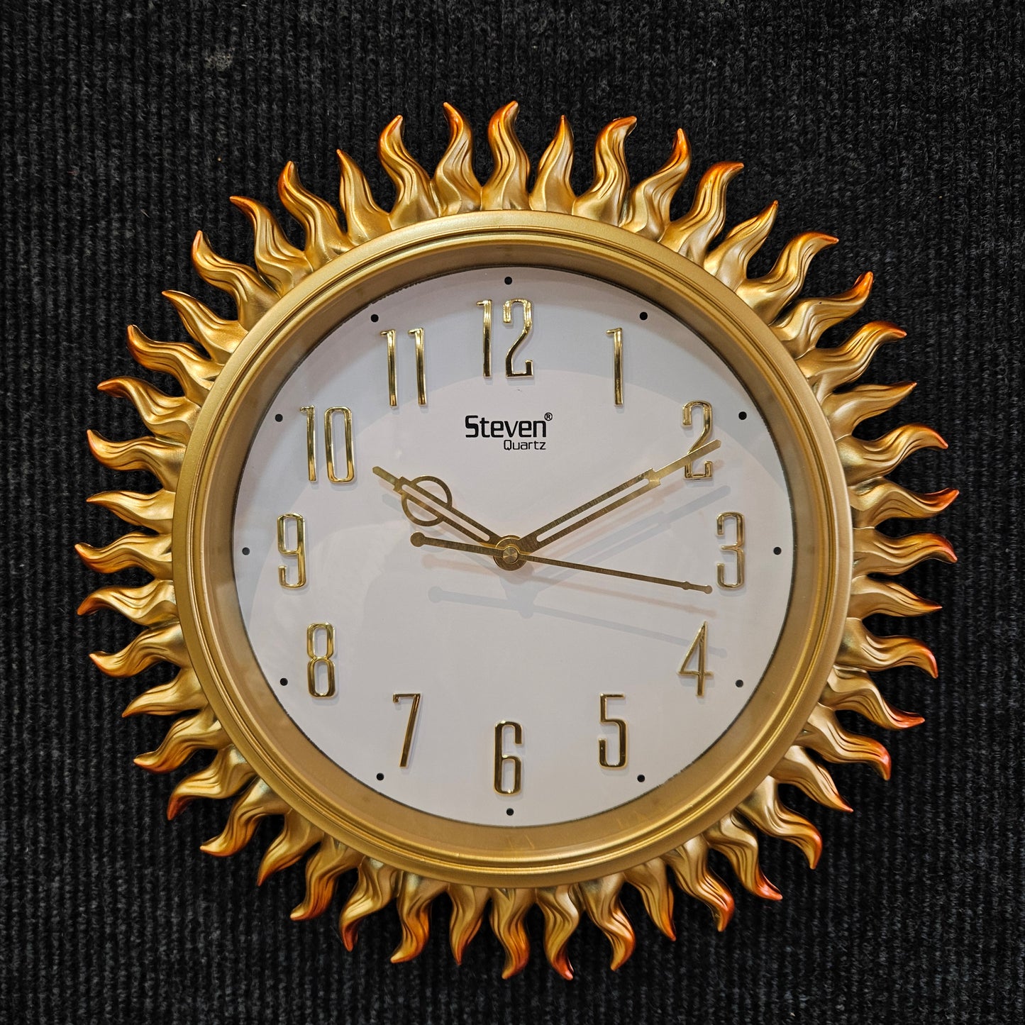 Gold sun-shaped wall clock on a black background