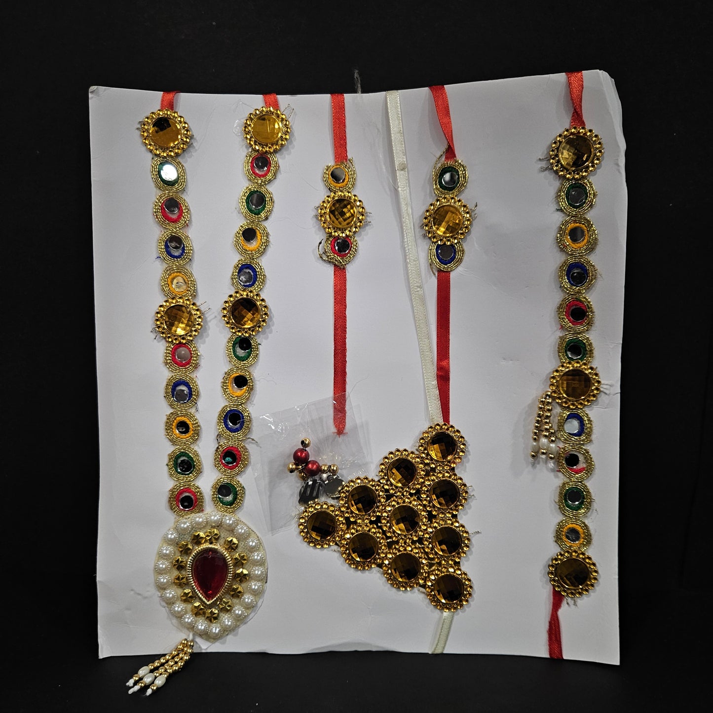 Set of gold and multicolored jewelry on a white paper with a black background