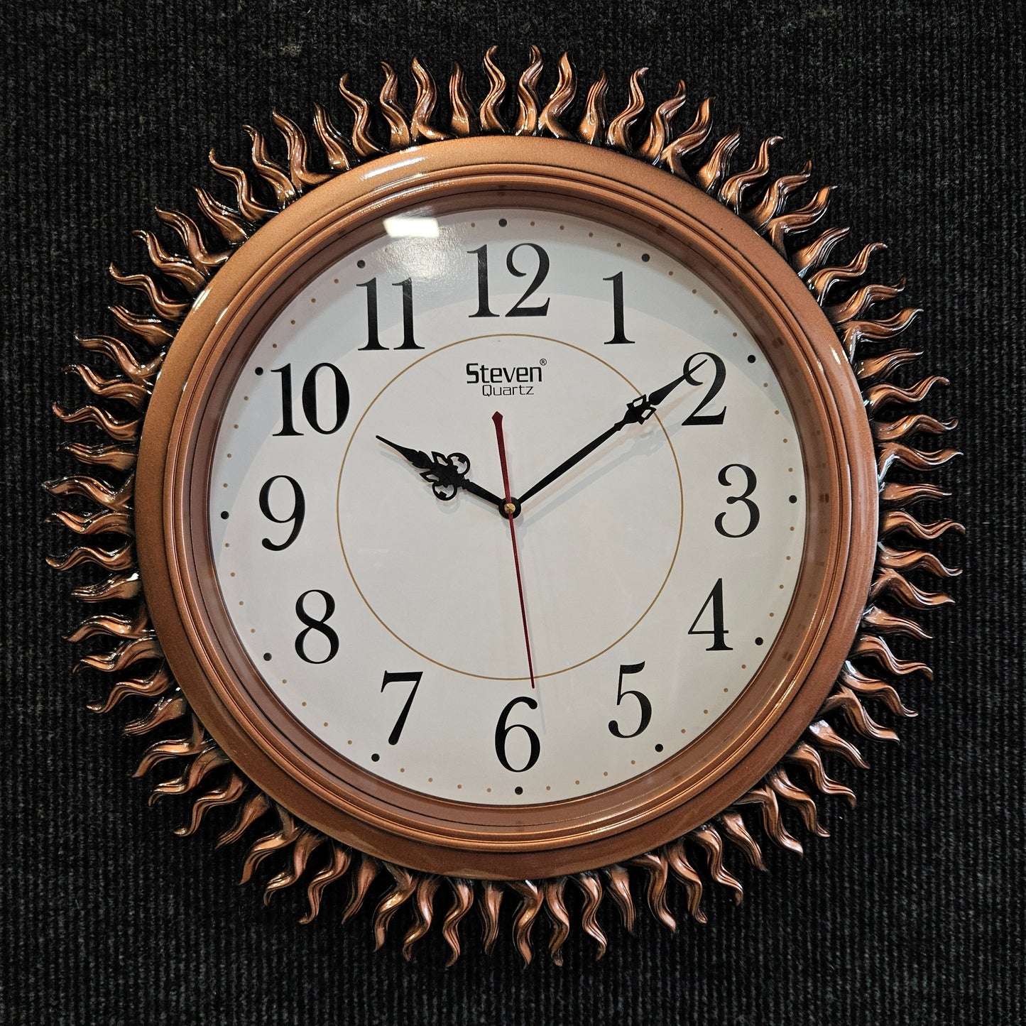 Decorative wall clock with sunburst design on a black background