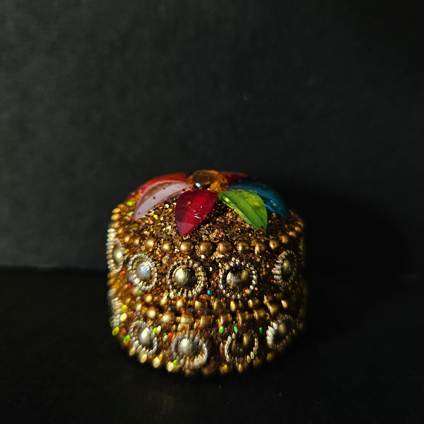 Decorative item with gold embellishments and colorful leaves on a dark background