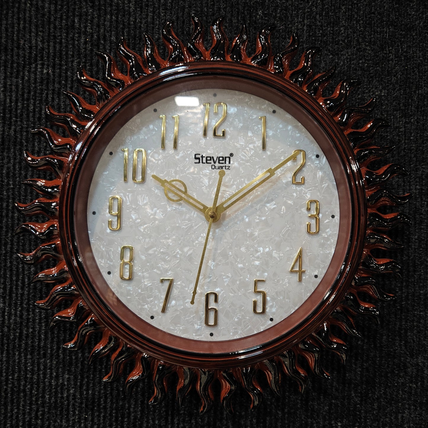 Decorative wall clock with sunburst design on a black background