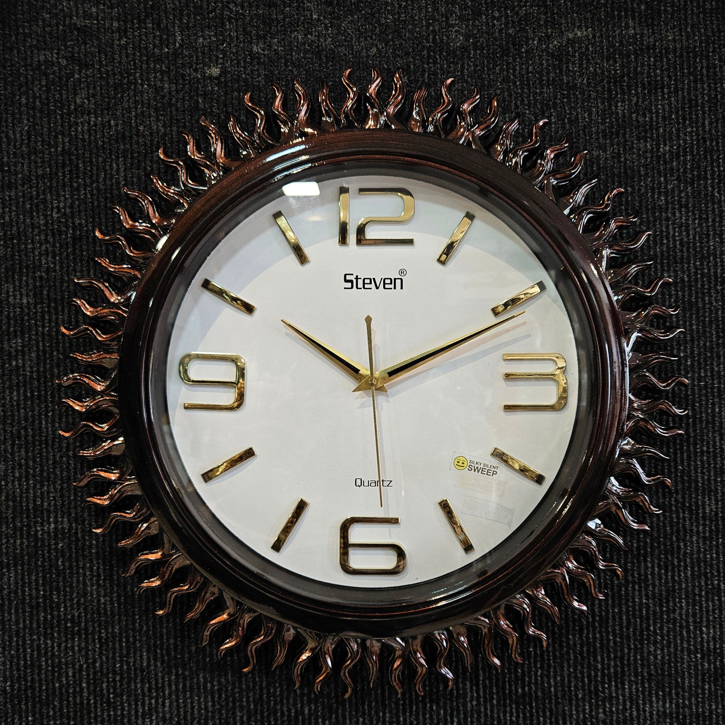 Decorative wall clock with gold Roman numerals on a black background