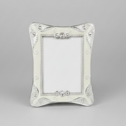A silver-colored metal photo frame with a couple kissing in an intimate setting displayed inside.