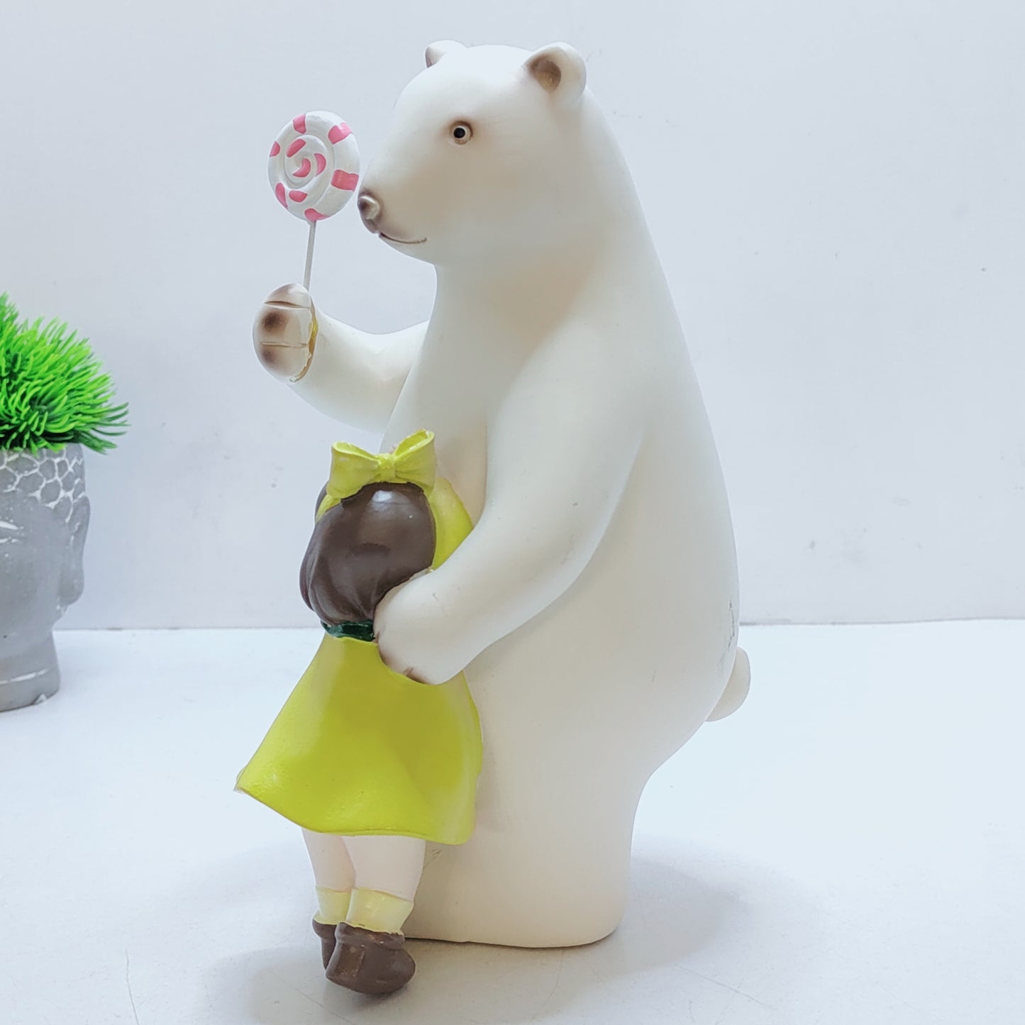 A bear hugs a baby, with a lollipop in his paw