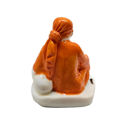 Shirdi Sai Baba statue made of marble, sitting on a base adorned with symbolic footprints.