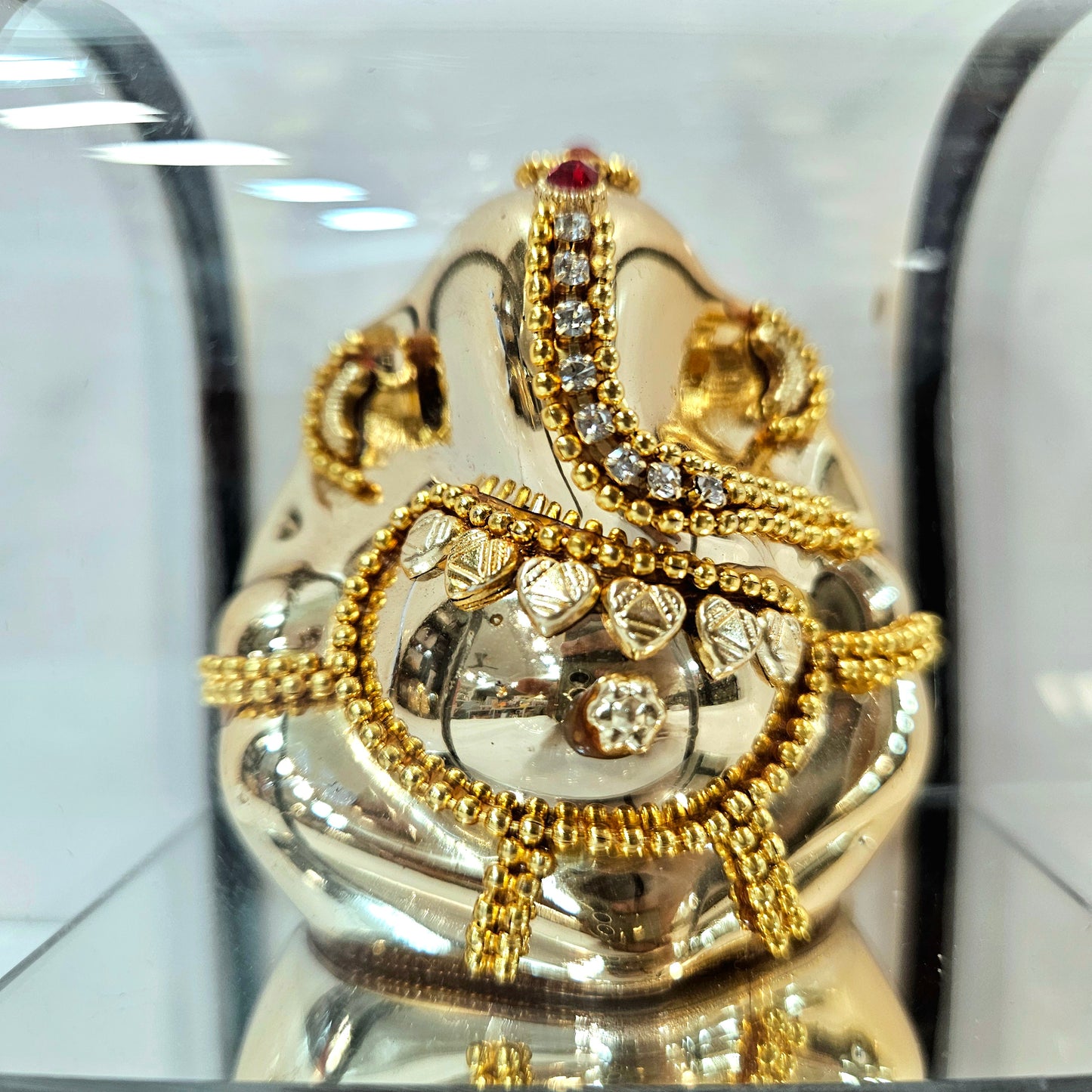 Lord vinayaka murti in a attractive look Decorated with stones designed in a transparent protective cabin