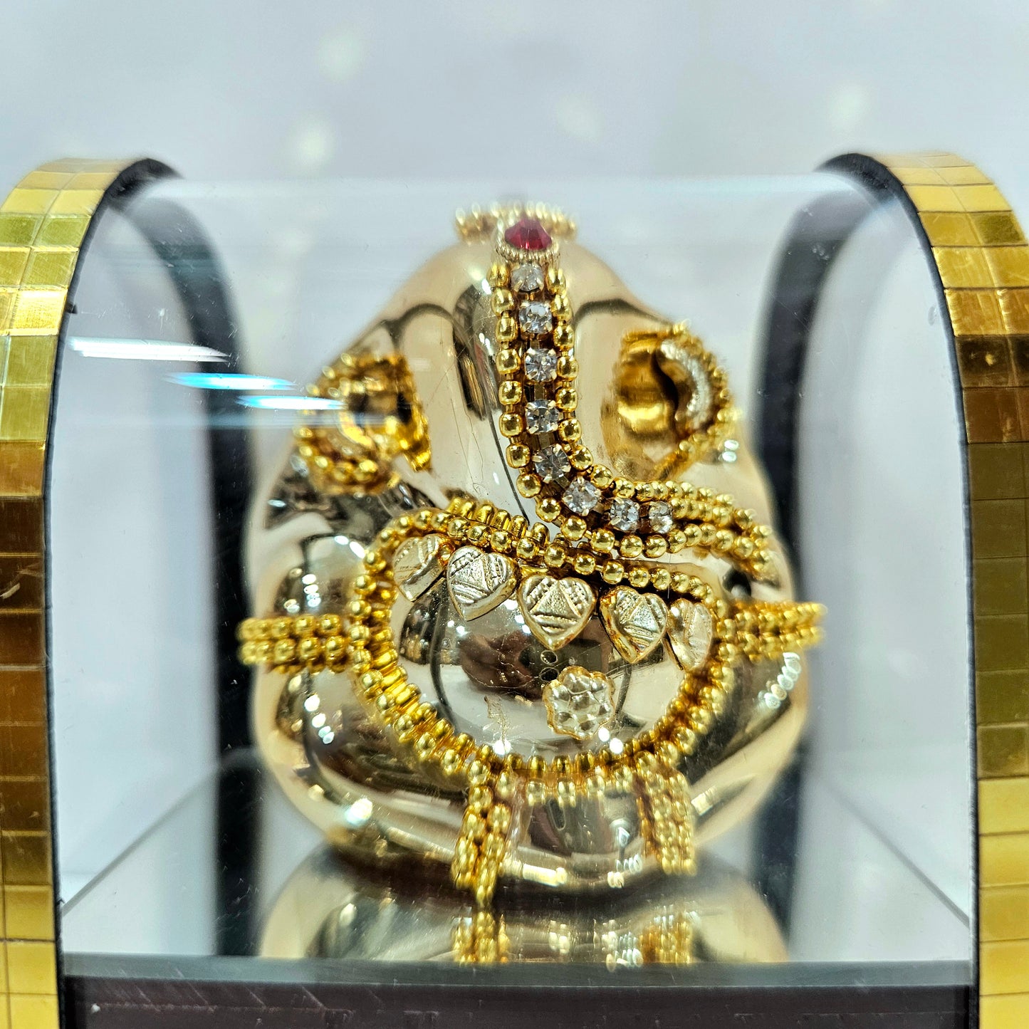Lord vinayaka murti in a attractive look Decorated with stones designed in a transparent protective cabin