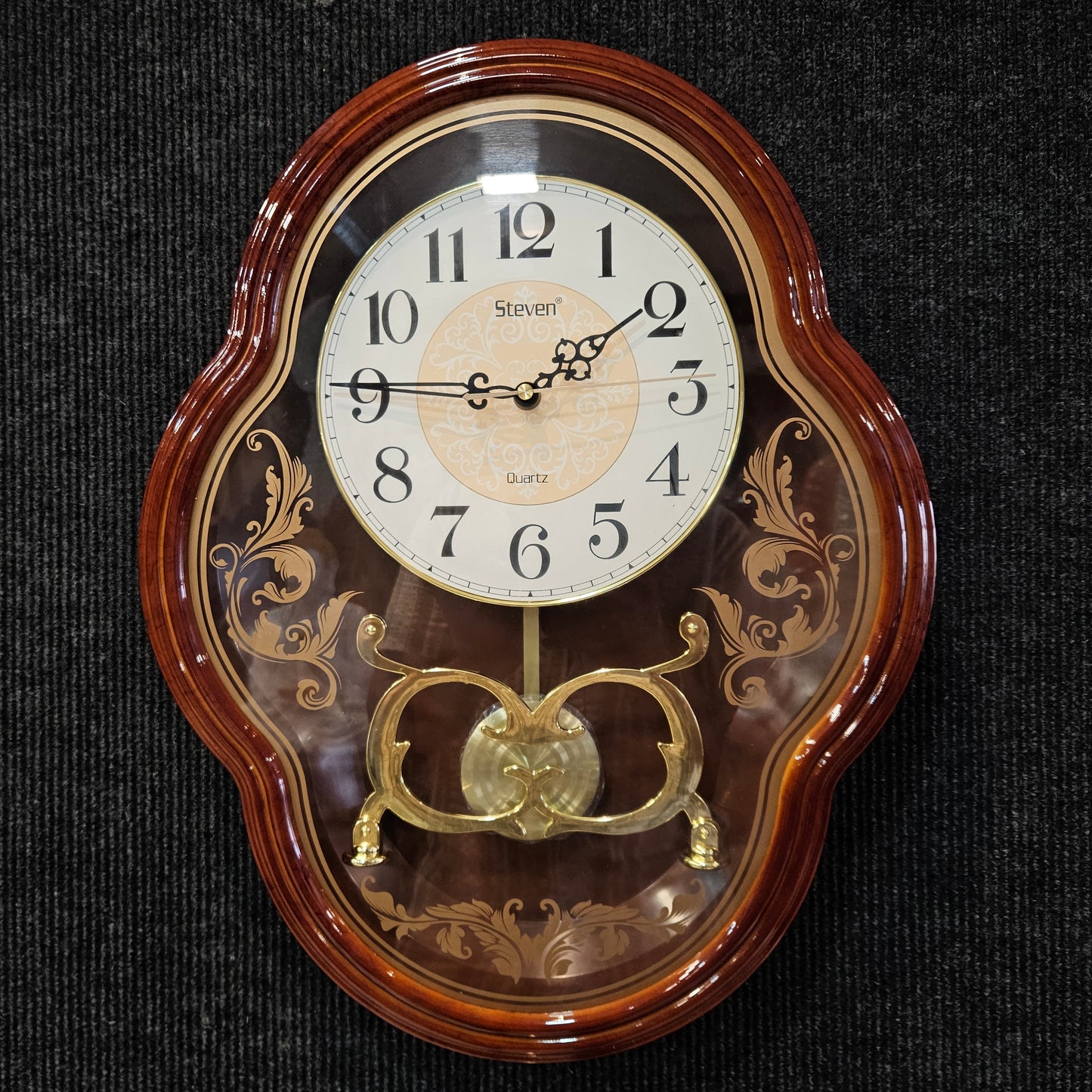 Decorative wall clock with wooden frame and gold accents on a dark background