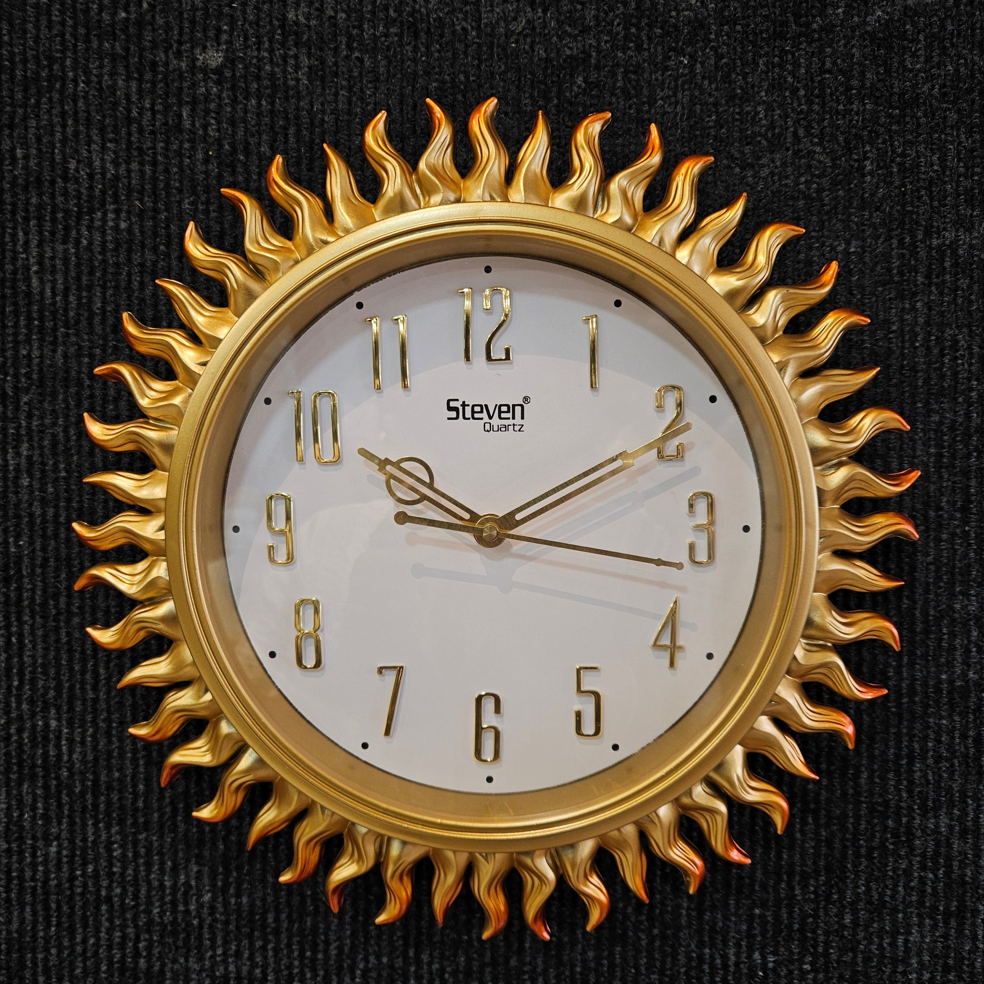 Gold sun-shaped wall clock on a black background