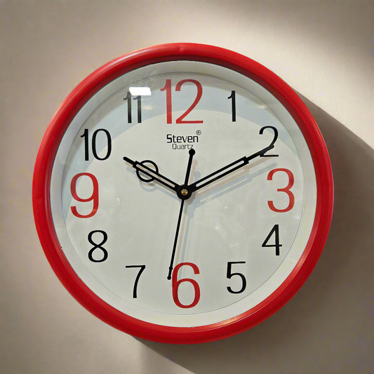Wall clock with red frame and white face on a black background
