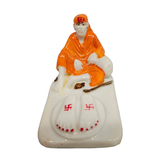 Shirdi Sai Baba statue made of marble, sitting on a base adorned with symbolic footprints.