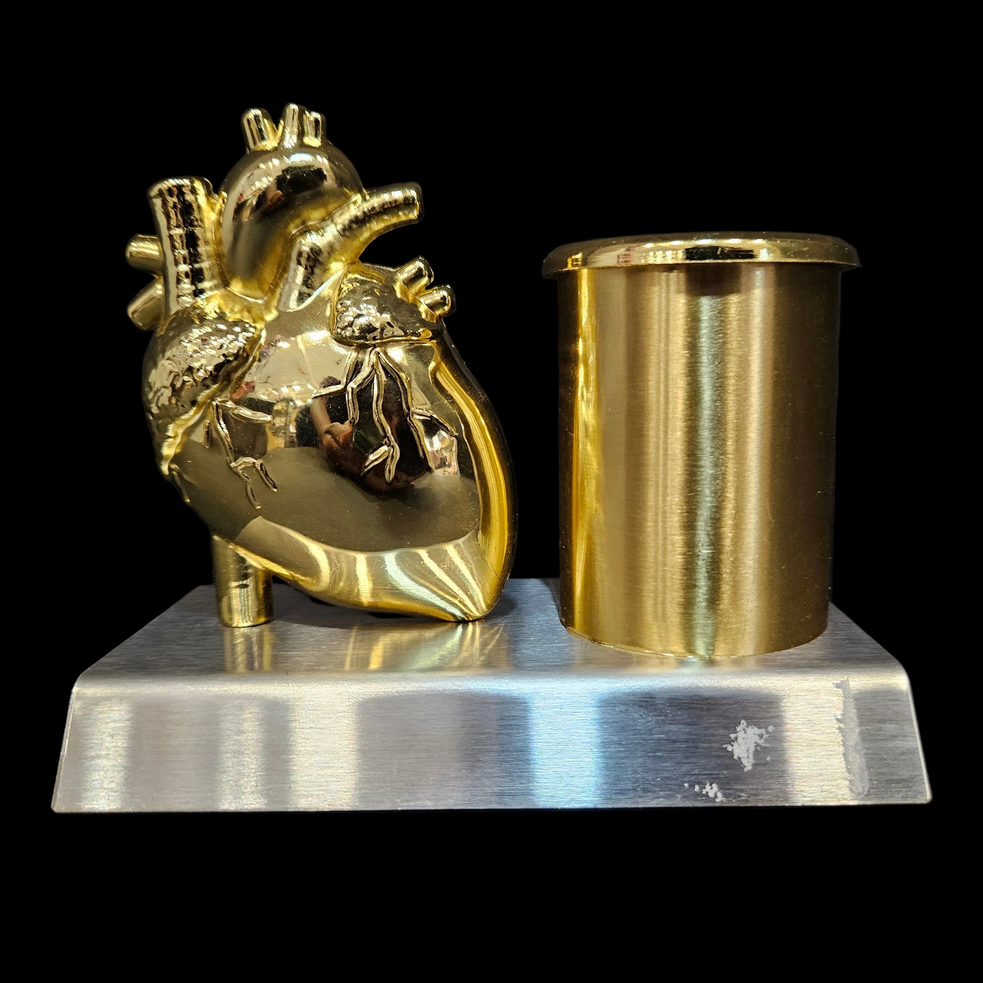 Gold anatomical heart sculpture on a black background
