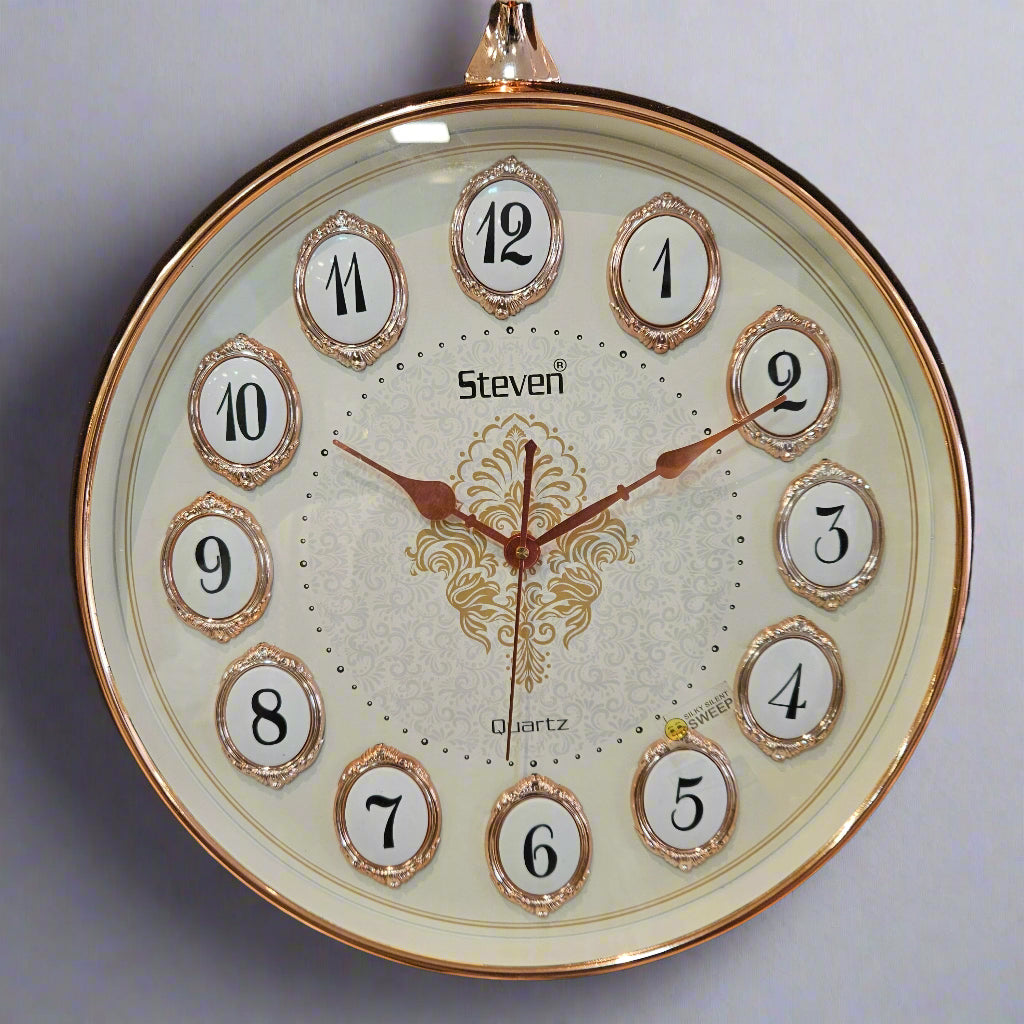 Round clock with gold frame and decorative design on a dark background