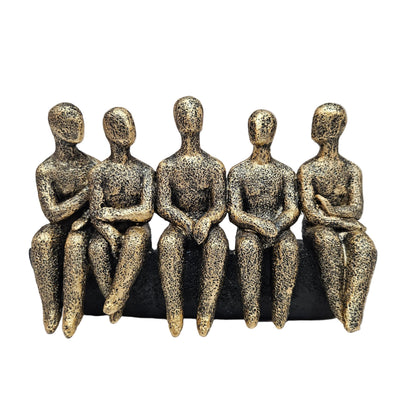 Abstract sculpture features five stylized figures seated together in a textured gold and black finish