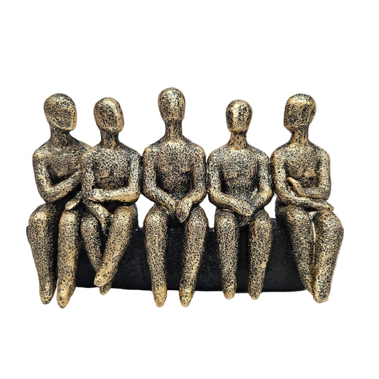 Abstract sculpture features five stylized figures seated together in a textured gold and black finish
