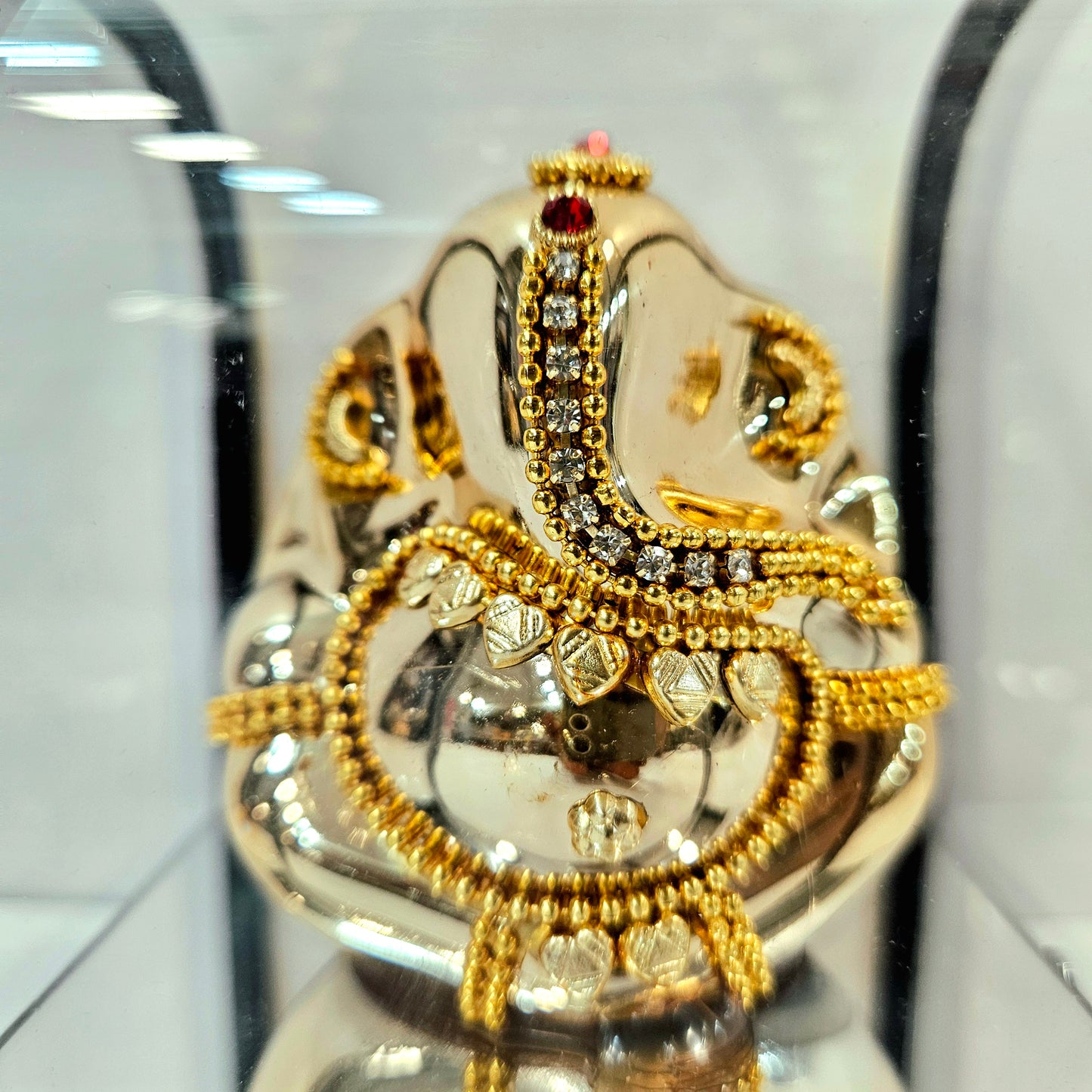 Lord vinayaka murti in a attractive look Decorated with stones designed in a transparent protective cabin