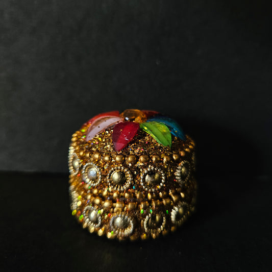 Decorative item with gold embellishments and colorful leaves on a dark background
