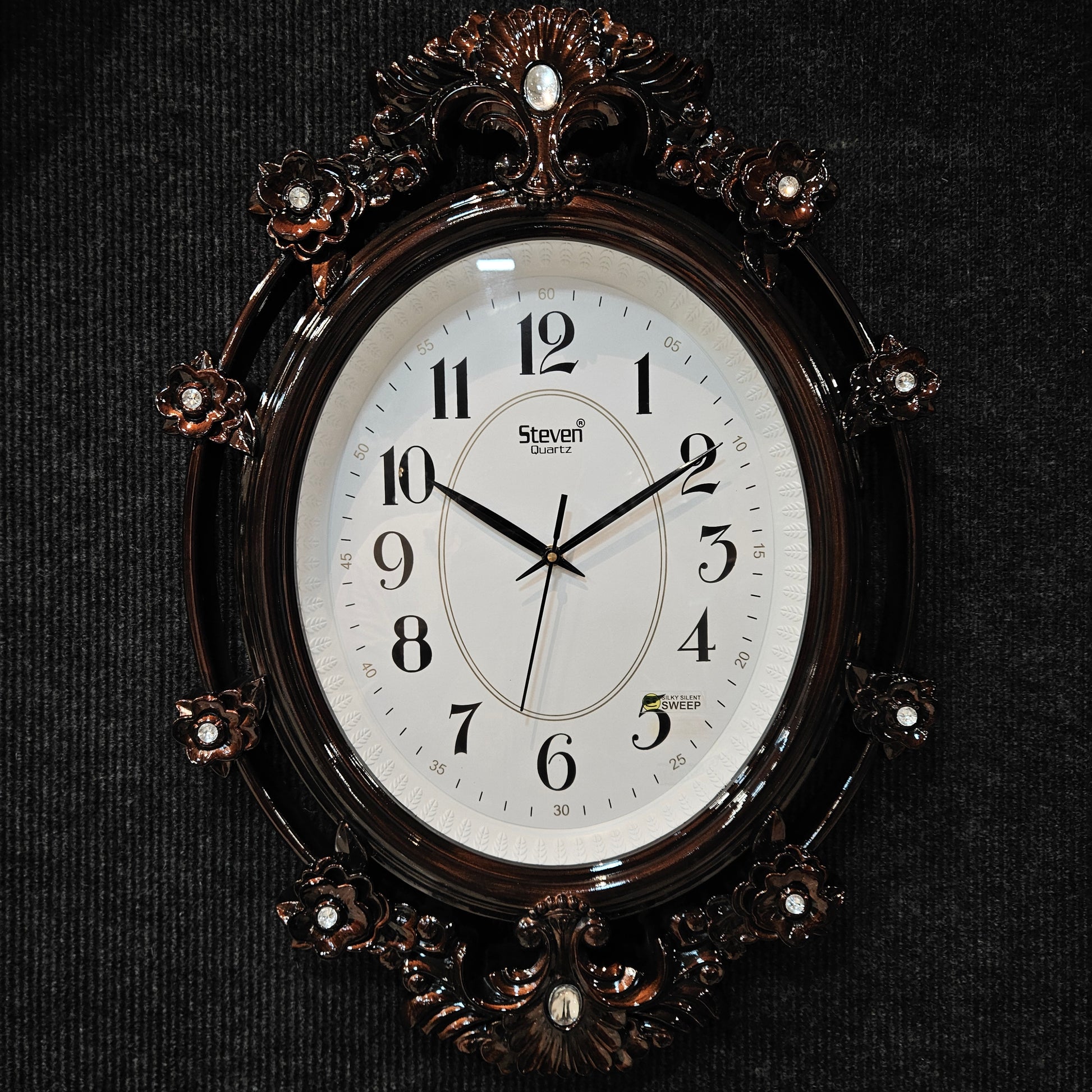 Decorative wall clock with floral designs on a black background