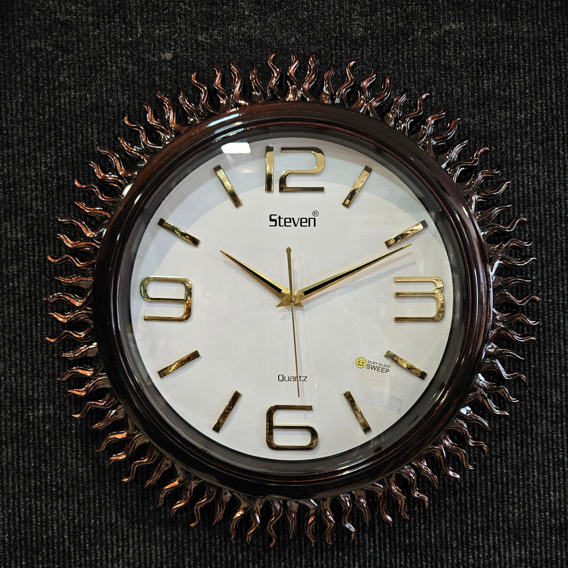 Decorative wall clock with gold Roman numerals on a black background
